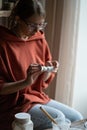 Concentrated woman sculptor making miniature porcelain figurine covered with white paint Royalty Free Stock Photo