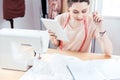 Concentrated woman seamstress working and using tablet in workshop