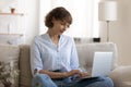 Concentrated woman sitting on sofa cross legged working on laptop Royalty Free Stock Photo