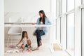 Concentrated woman using laptop while her daughter sitting on floor. Royalty Free Stock Photo