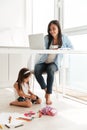 Concentrated woman using laptop while her daughter sitting on floor. Royalty Free Stock Photo