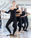 Woman practicing demi plie at barre during group ballet class