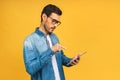 Confident young handsome man in casual working on laptop while standing against yellow background Royalty Free Stock Photo