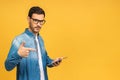 Confident young handsome man in casual working on laptop while standing against yellow background Royalty Free Stock Photo