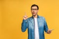 Concentrated on work. Confident young handsome man in casual working on laptop while standing against yellow background. Royalty Free Stock Photo