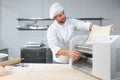 Concentrated at work. Handsome chef rolling a dough through pasta machine Royalty Free Stock Photo