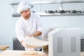 Concentrated at work. Handsome chef rolling a dough through pasta machine Royalty Free Stock Photo