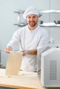 Concentrated at work. Handsome chef rolling a dough through pasta machine Royalty Free Stock Photo