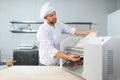 Concentrated at work. Handsome chef rolling a dough through pasta machine Royalty Free Stock Photo