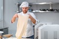 Concentrated at work. Handsome chef rolling a dough through pasta machine Royalty Free Stock Photo
