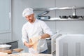 Concentrated at work. Handsome chef rolling a dough through pasta machine Royalty Free Stock Photo