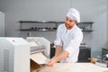Concentrated at work. Handsome chef rolling a dough through pasta machine Royalty Free Stock Photo