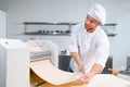 Concentrated at work. Handsome chef rolling a dough through pasta machine Royalty Free Stock Photo