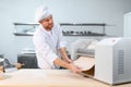 Concentrated at work. Handsome chef rolling a dough through pasta machine Royalty Free Stock Photo