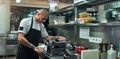 Concentrated at work. Serious and handsome chef with black tattoos on his hands rolling a black dough through pasta Royalty Free Stock Photo