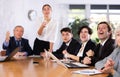 Concentrated young adult old office workers sitting around the table and looking at screen in office Royalty Free Stock Photo