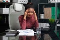 Thoughtful young African-American businesswoman holding hands behind her head and working with documents at Desk in Royalty Free Stock Photo
