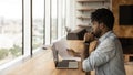Concentrated young african man read printed document before laptop screen