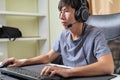 Concentrated young Asian esport gamer man looking monitor playing computer online skills game, pay attention in competition at Royalty Free Stock Photo