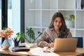 Concentrated asian woman working on computer laptop at her office desk. Royalty Free Stock Photo