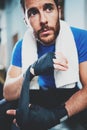 Concentrated Young athlete tying black boxing bandages.Boxer man prepairing before kickboxing training in gym. Blurred Royalty Free Stock Photo