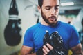 Concentrated Young athlete tying black boxing gloves.Bearded Boxer man prepairing before kickboxing training session in Royalty Free Stock Photo