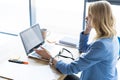 Concentrated young beautiful businesswoman working on laptop in bright modern office. Royalty Free Stock Photo