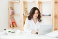 Concentrated young beautiful businesswoman working on laptop and document in bright modern office Royalty Free Stock Photo