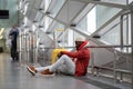 Concentrated young black man sitting on floor airport near window using mobile phone waiting flight. Royalty Free Stock Photo