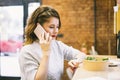 Concentrated young business woman having phone call during lunch time in the cafe. Remote work, freelancer work place Royalty Free Stock Photo