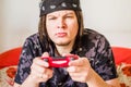 Concentrated young caucasian man with dreadlocks sitting on the couch playing video games Royalty Free Stock Photo