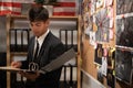 Concentrated young detective in black suit reading dossier in dark office. Investigator working with criminal case Royalty Free Stock Photo