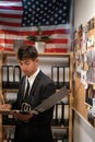 Concentrated young detective in black suit reading dossier in dark office. Investigator working with criminal case Royalty Free Stock Photo