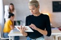 Concentrated young entrepreneur woman using her digital tablet while standing in the office Royalty Free Stock Photo