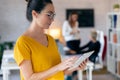 Concentrated young entrepreneur woman using her digital tablet while standing in the office Royalty Free Stock Photo