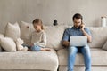 Concentrated young father working on laptop, while kid playing. Royalty Free Stock Photo