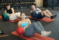 Strong young woman performing exercise for abs core with medicine ball on yoga mat during group workout in CrossFit gym Royalty Free Stock Photo