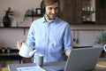 Concentrated young freelancer businessman using laptop for video conferance, working remotely online at home