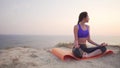 Concentrated young girl meditates with closed eyes at sunset.