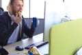 Concentrated young man in casual clothing using computer, streaming playthrough or walkthrough video and eating chips Royalty Free Stock Photo