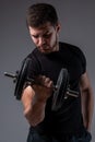 Concentrated young man performing bicep curl with dumbbell Royalty Free Stock Photo