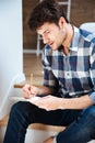 Concentrated young man sitting and writing in notepad at home Royalty Free Stock Photo