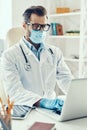 Concentrated young man in white lab coat and protective mask Royalty Free Stock Photo