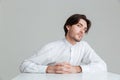 Concentrated young man in white shirt sitting at the table Royalty Free Stock Photo