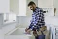 Concentrated young man work with white cabinet in the kitchen Royalty Free Stock Photo