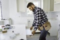 Concentrated young man work with white cabinet in the kitchen Royalty Free Stock Photo