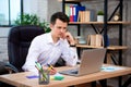 Concentrated young manager man sitting at office desk working on laptop computer and thinking about solving a financial problem Royalty Free Stock Photo