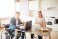 Concentrated young man on wheelchair working with laptop and eating salad. Studying with disability and inclusiveness Royalty Free Stock Photo