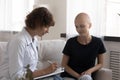 Concentrated young oncologist handwriting prescription to cancer patient.