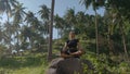 Concentrated young sportswoman practices yoga on big stone in tropical rainforest healthy lifestyle